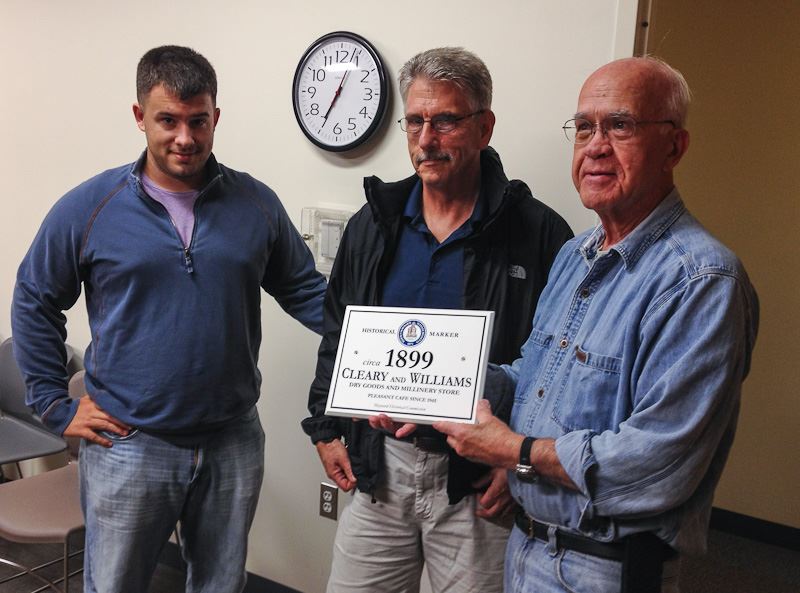 Three men holding a 1899 Cleary and Williams sign