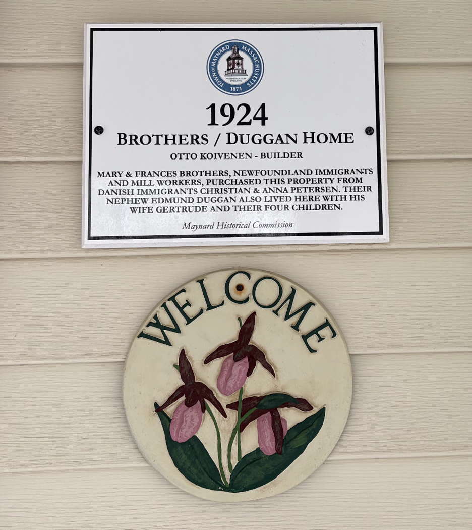 White historic house plaque with black text and \"welcome\" sign