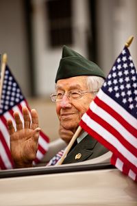 And older veteran in a car between two American flags