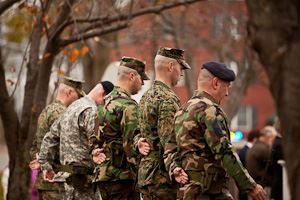 Officers in camouflage with an arm behind their back and heads bent